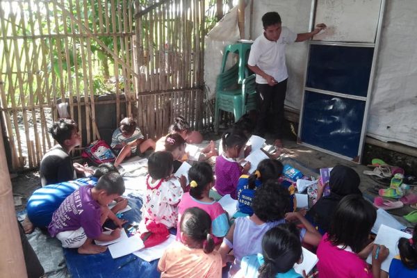 Volunteer teachers engaging with children outdoors in Tangerang, Indonesia, warm afternoon light